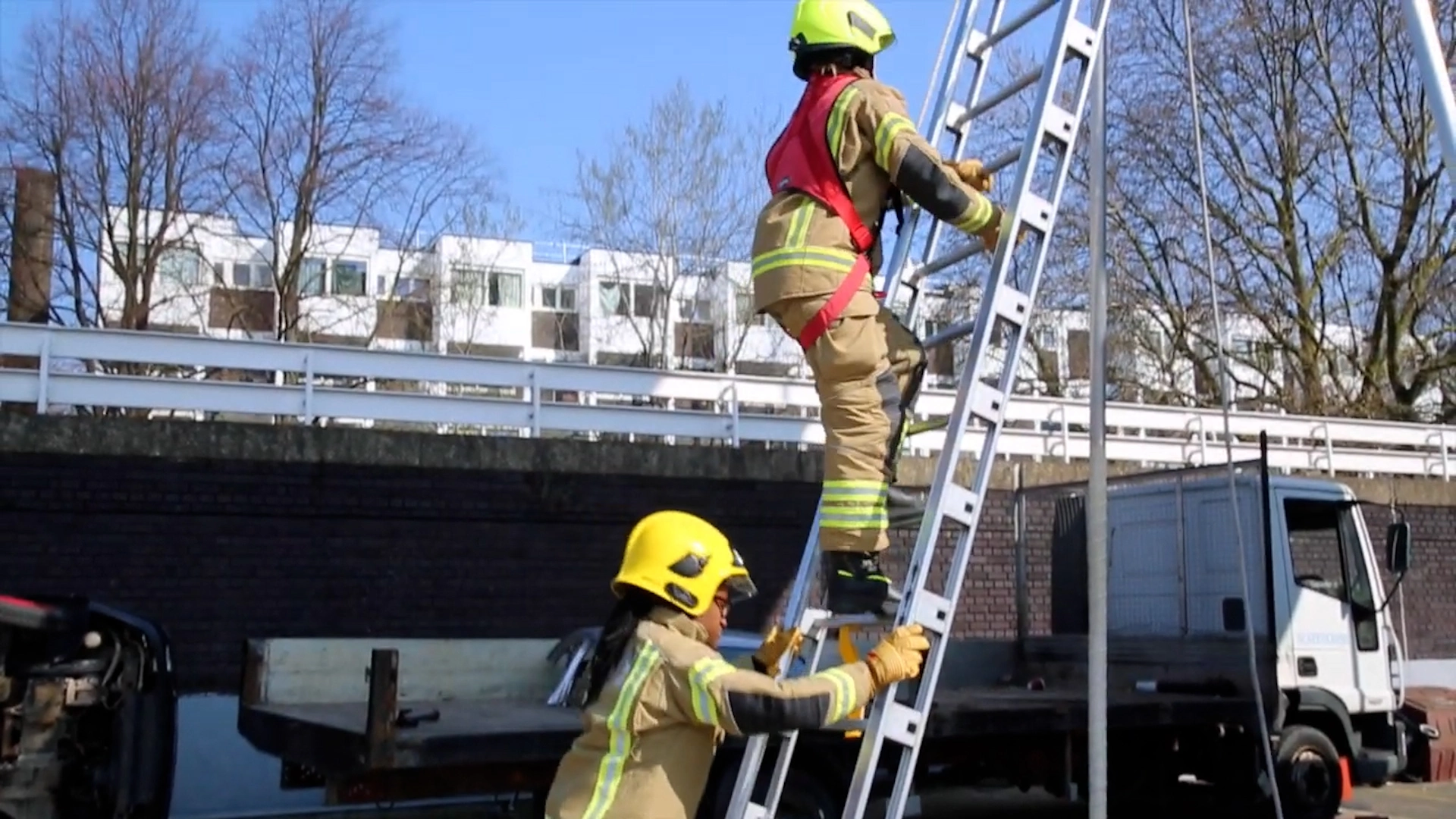 A firefighter is climbing a ladder as part of a Job Function Test to determine if they are able to perform the physical requirements of the job.